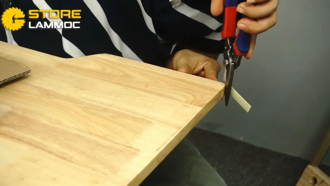 Cận cảnh kéo WORKPRO đang cắt dải nẹp, lưỡi và tay cầm màu đỏ-xanh rõ nét