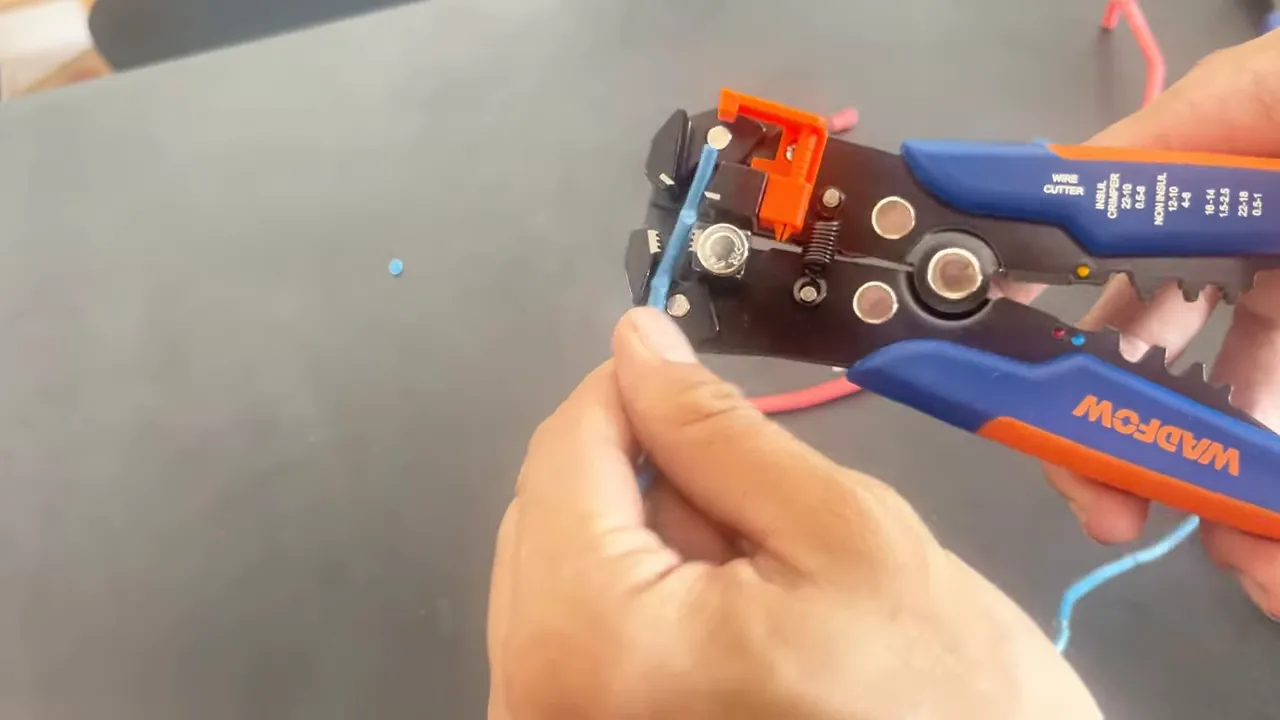 Kìm Wadfow đang đưa dây vào khe tuốt, thấy rõ đầu kìm, tay cầm và dây