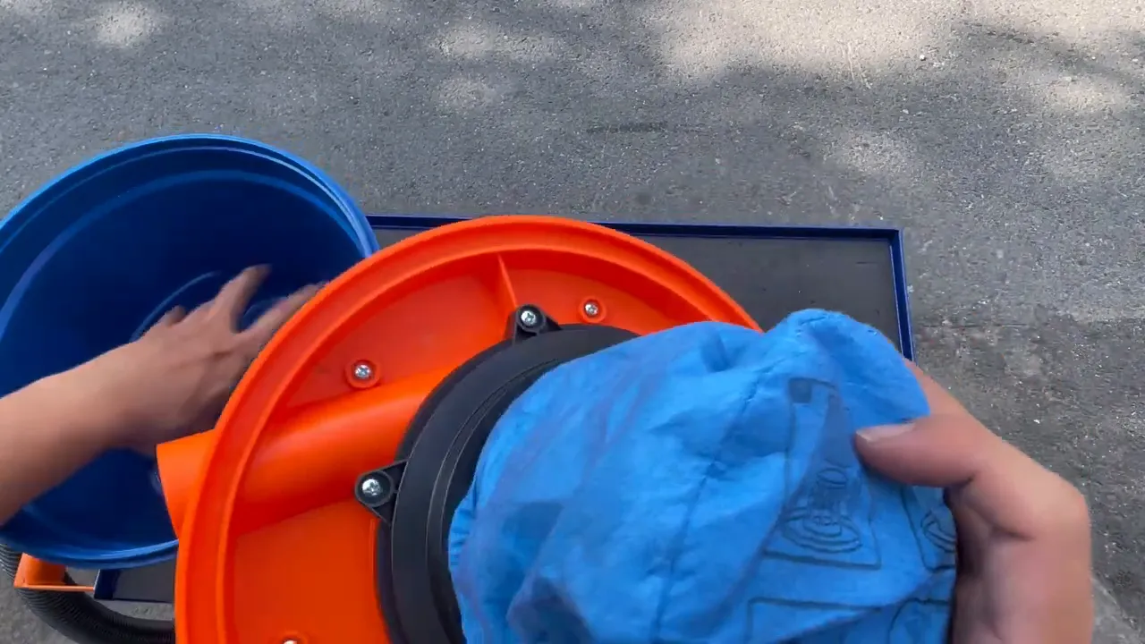 Lắp lớp mút vào túi lọc vải của máy hút bụi WADFOW, tay đang giữ nắp màu cam và túi vải màu xanh