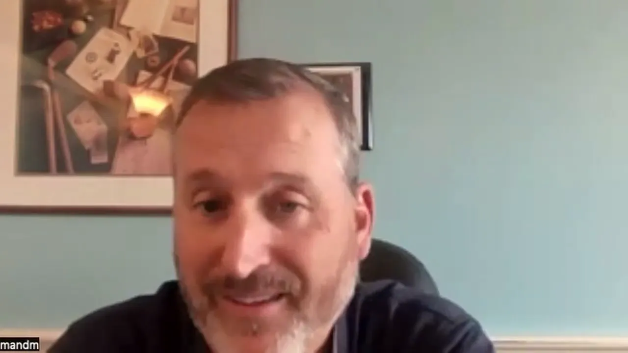 Well-lit, centered webcam screenshot of a presenter speaking about card pricing with a teal wall background