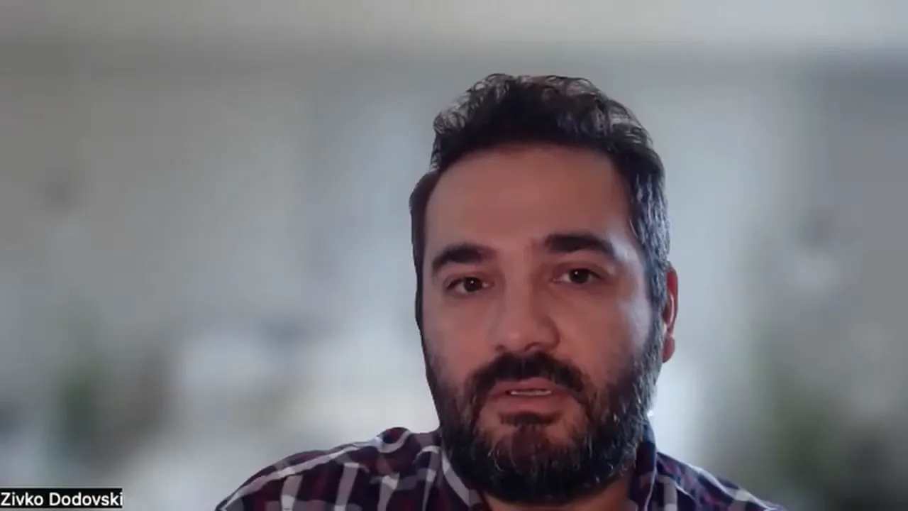 Video conference speaker close-up with blurred background speaking to camera.