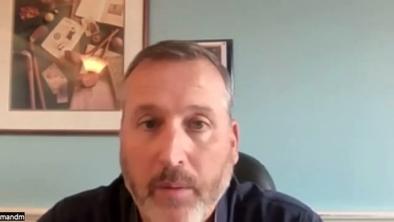 Frontal, high-clarity video-call screenshot of a presenter addressing invoicing options with a teal wall and framed art behind him