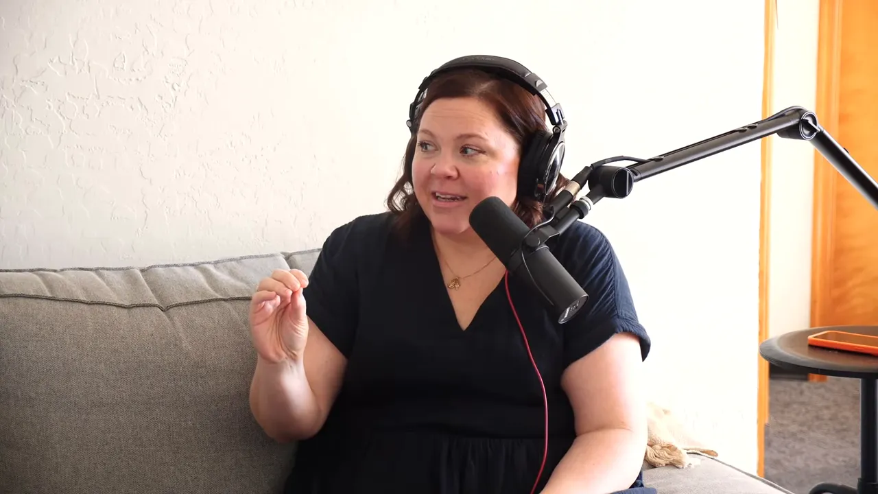 podcast host demonstrating a small pinching gesture while speaking into a microphone