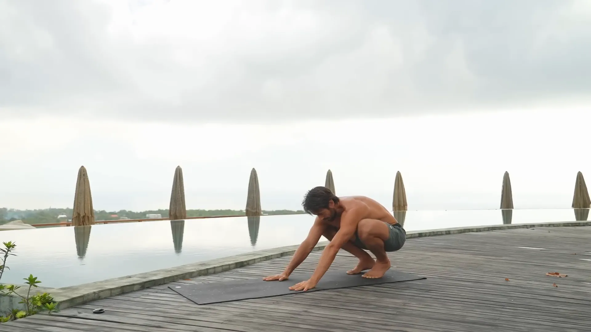 Squatting with arms reaching forward to engage upper back