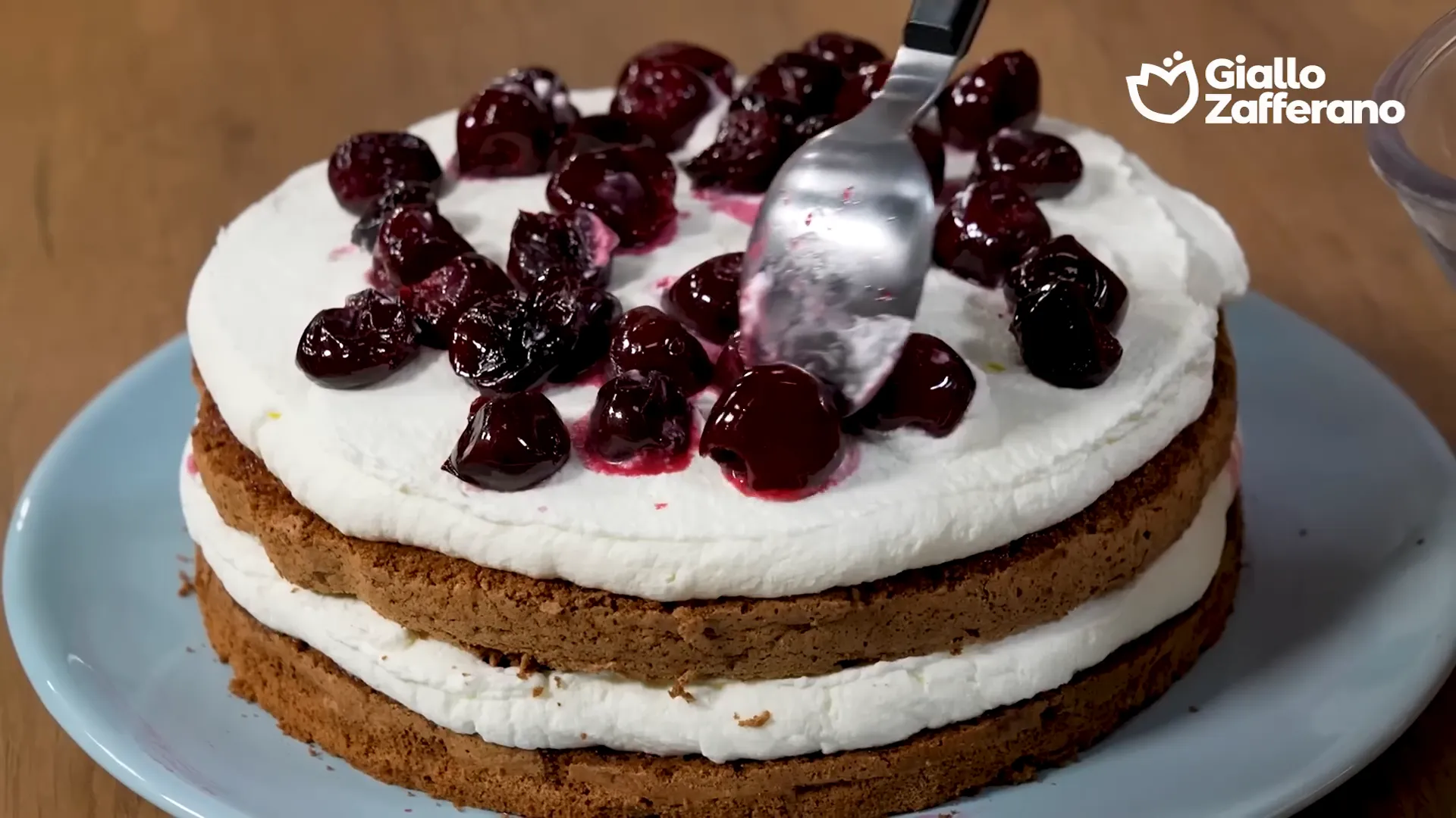 Assemblaggio della torta con crema chantilly e ciliegie