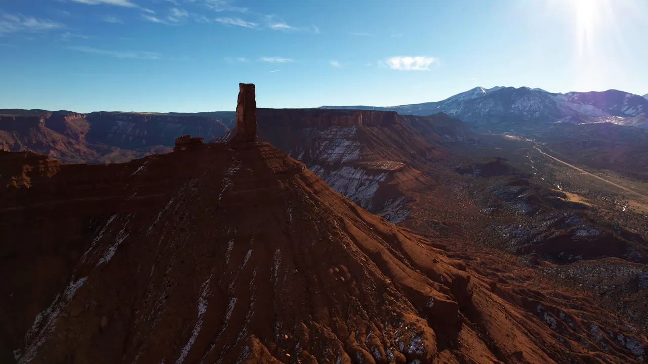 Castle Tower sandstone spire on a ridge with La Sal Mountains in the distance