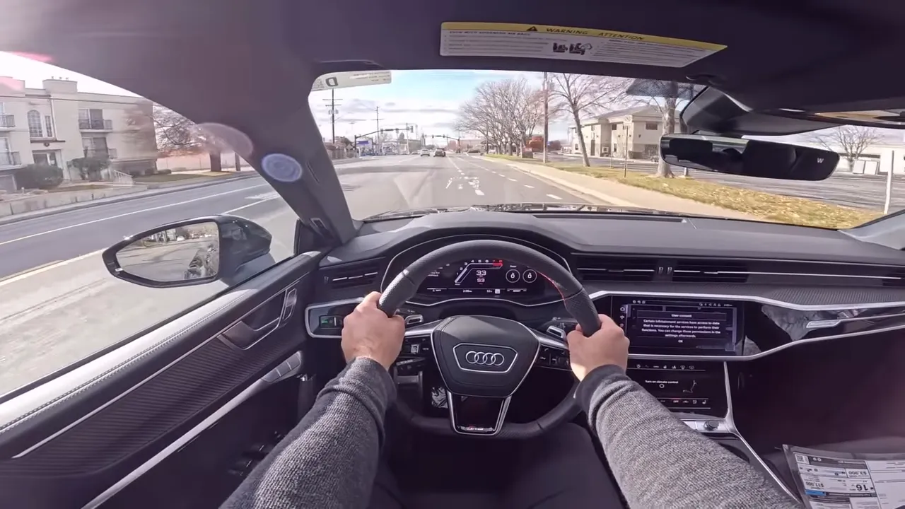 Wide Audi RS7 driver view with hands on steering wheel, digital dash, dual infotainment screens and clear road ahead