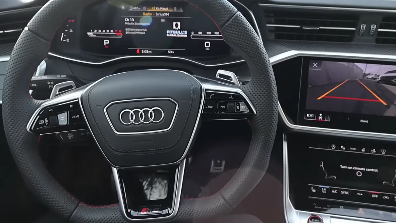 Audi RS7 cockpit showing perforated steering wheel, paddle shifters, digital instrument cluster and dual infotainment screens