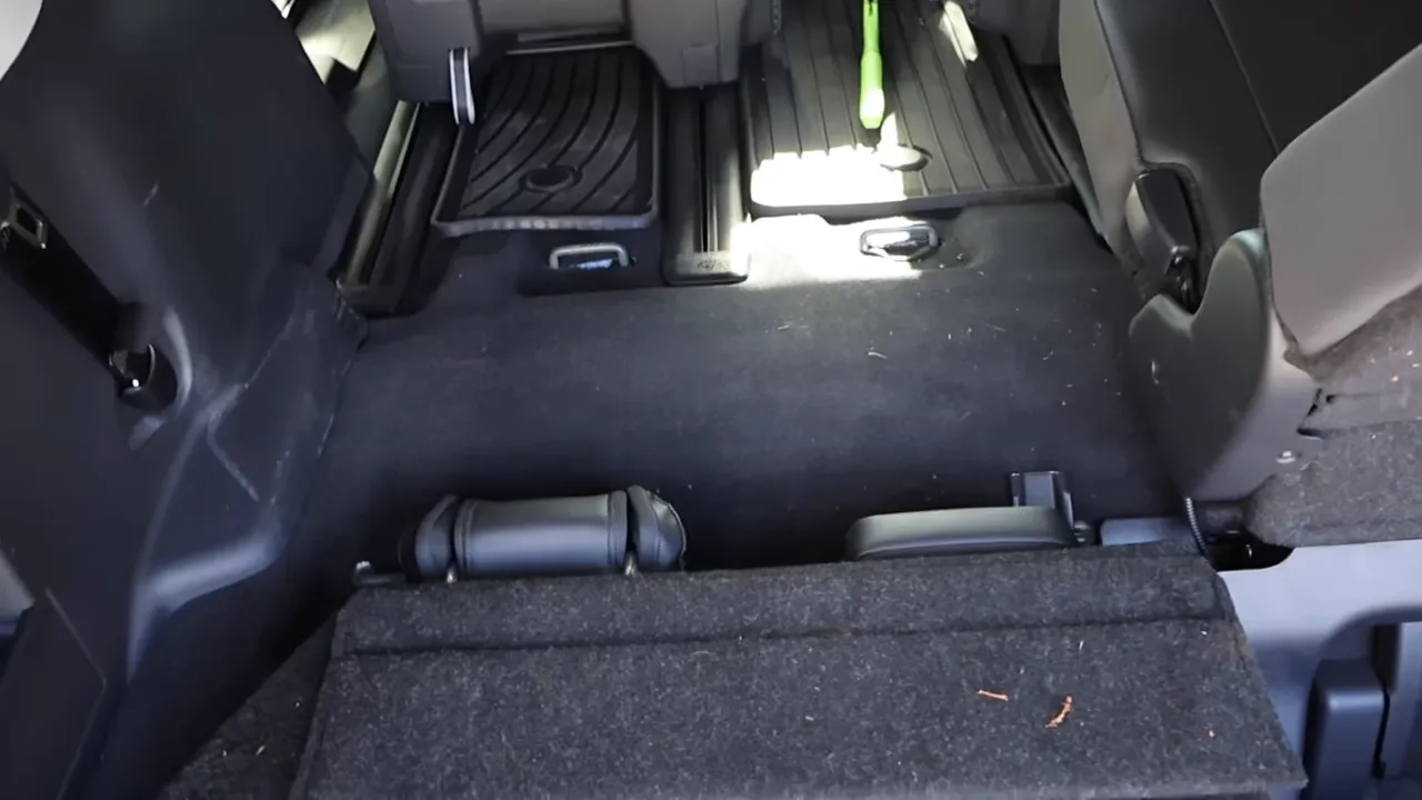 Rear cargo area showing raised third-row floor, folded seats and wheel-well intrusions