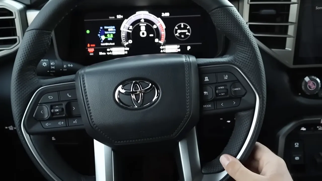 Close-up of Toyota steering wheel with perforated leather, steering controls and instrument cluster behind