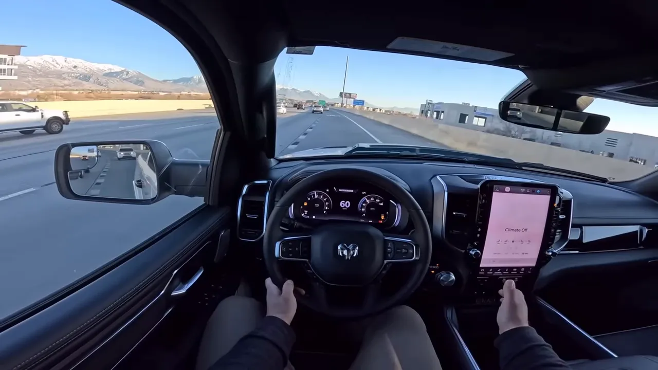 Driver POV inside Ram 1500 showing steering wheel, digital instrument cluster reading 60 mph and center infotainment screen