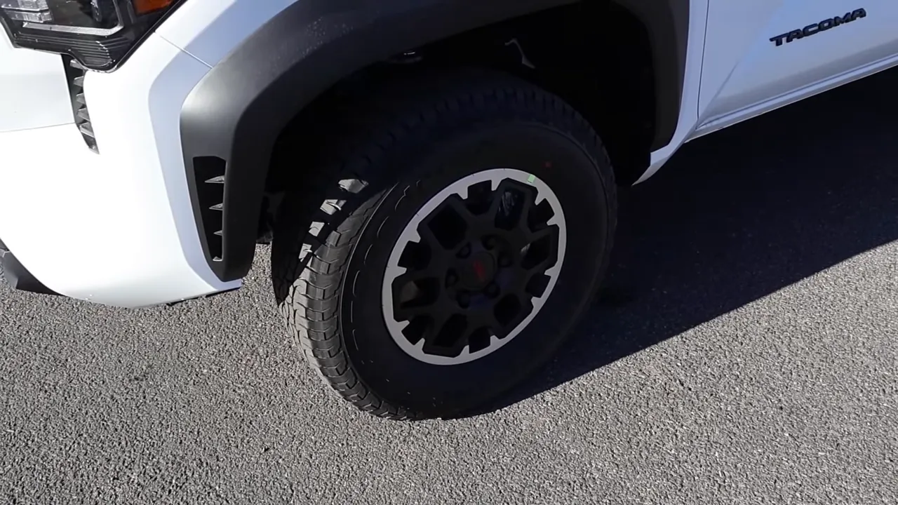 Front wheel and tire on a Tacoma with fender flare and Tacoma badge visible, highlighting the wheel design and tire profile.