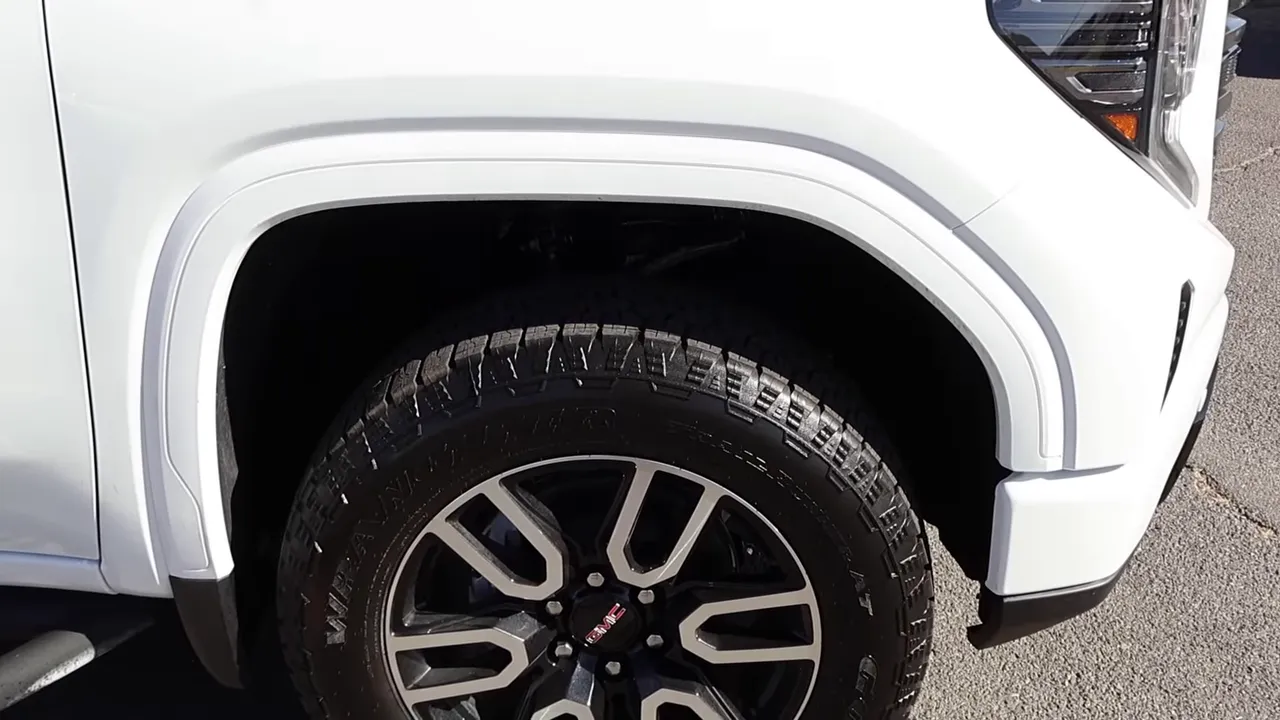 Side view of a 2026 GMC Sierra 1500 AT4 showing lifted wheel arch, body‑painted fender flare and two‑tone 275/60/20 wheel.