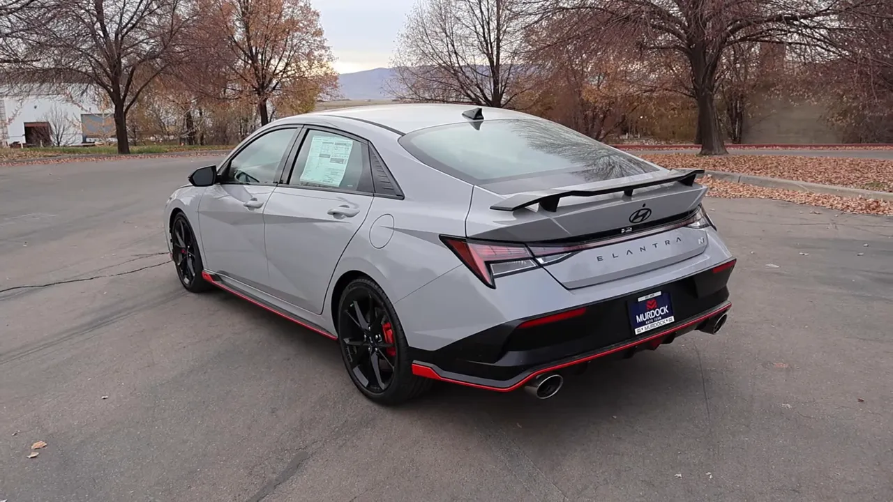 2026 Hyundai Elantra N rear three-quarter view showing spoiler, full-width light bar, red trim and quad-tip exhaust.