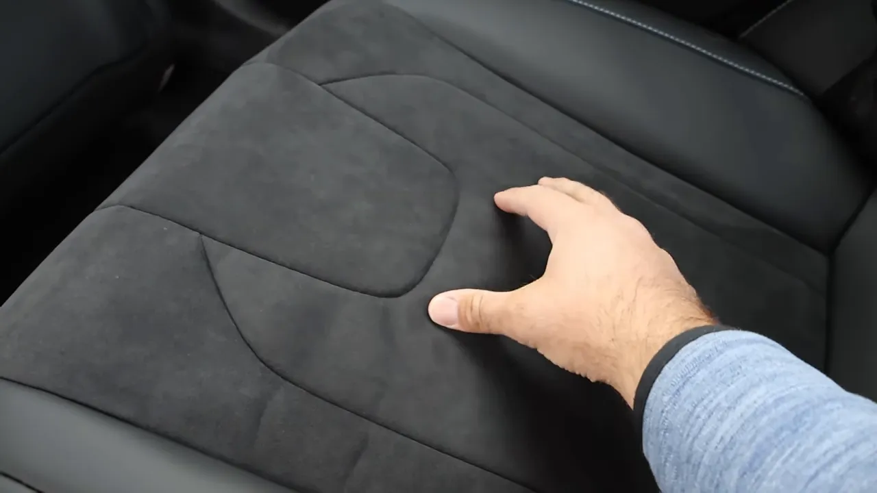 hand pressing Alcantara seat cushion to show material and firmness