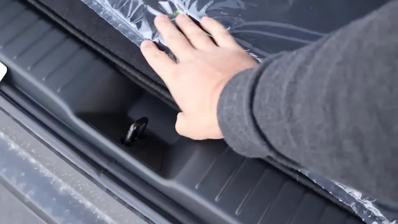 Hand lifting the Mazda CX‑50 load floor to reveal the under‑floor storage compartment