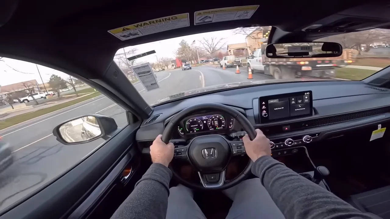 Driver point-of-view of Honda CR-V showing steering wheel, dashboard and roadside work truck with cones