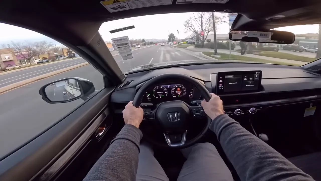 Centered driver POV in Honda CR-V with both hands on wheel showing instrument cluster, infotainment and road