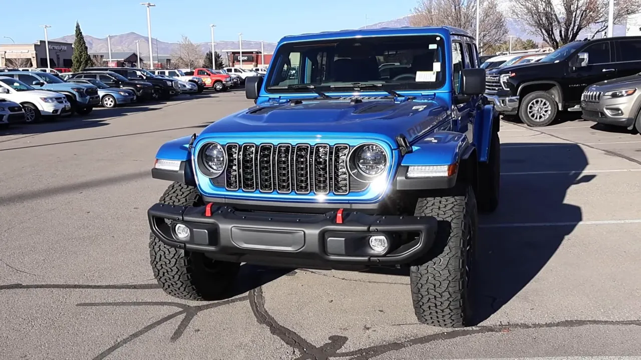 full front three-quarter view of blue Jeep Wrangler Rubicon X showing grille bumper and tow hooks
