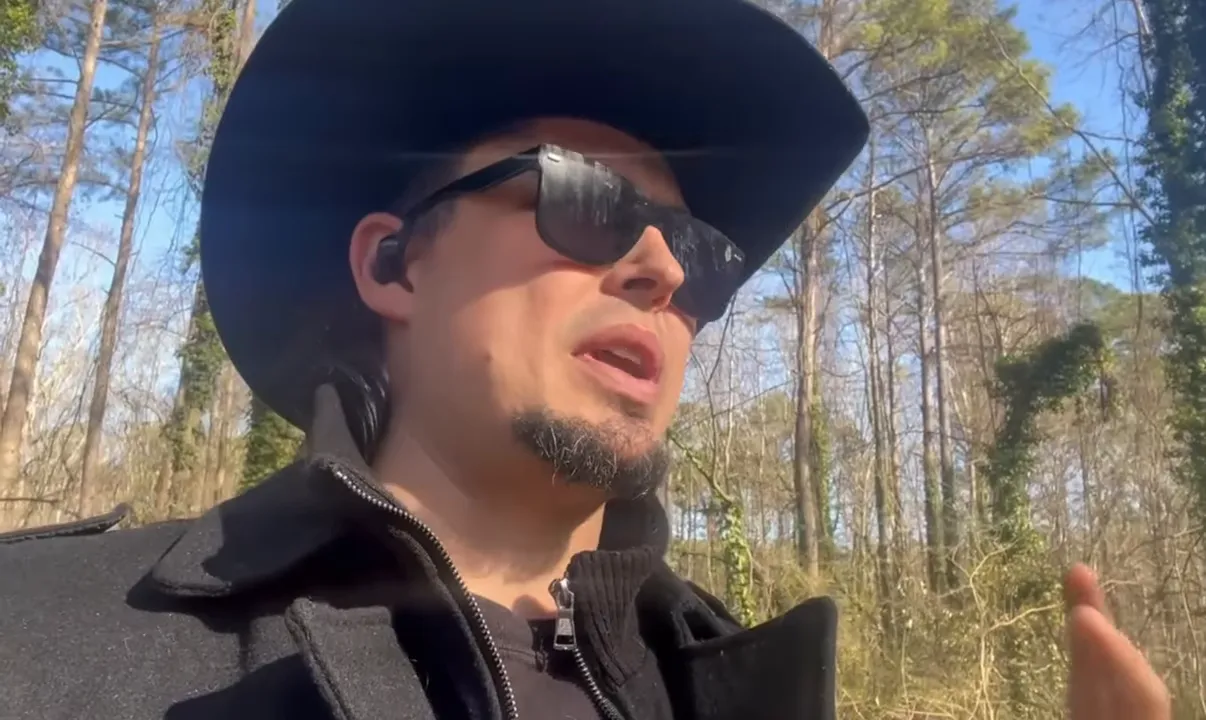 Presenter gesturing while explaining Bitcoin's market reaction outdoors in sunglasses and hat