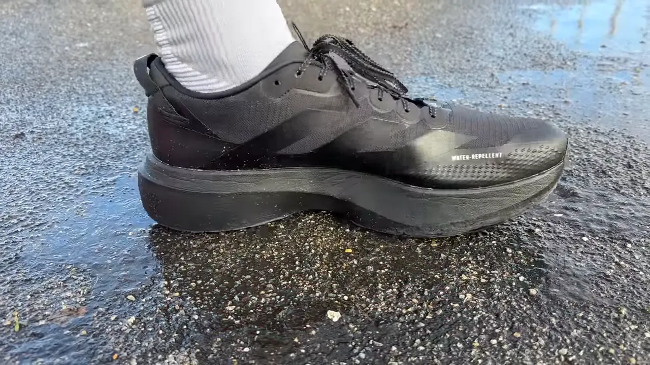 Side profile close-up of black Adidas EVO SL ATR on wet ground with visible 'water-repellent' text
