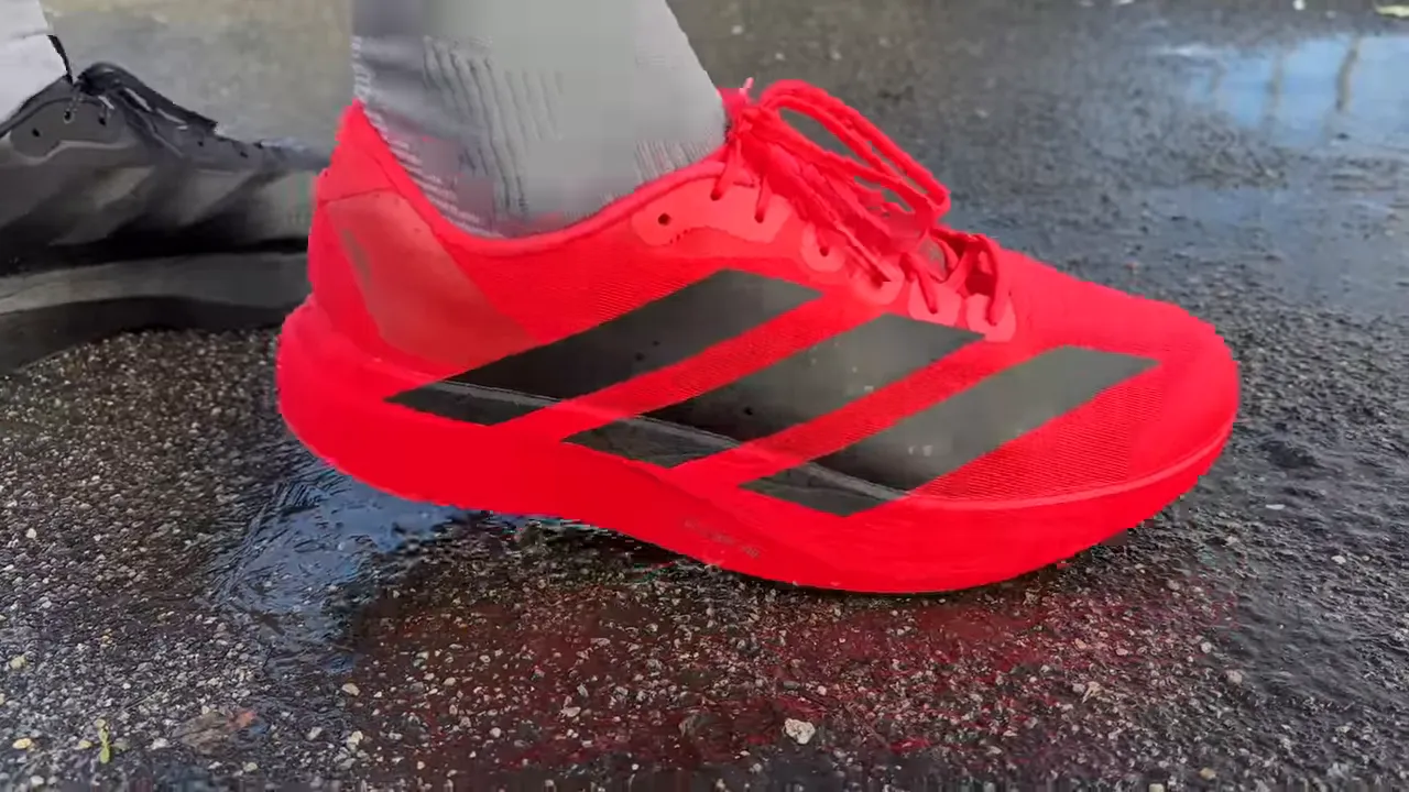 Bright red Adidas Evo SL close-up on wet pavement showing upper and midsole