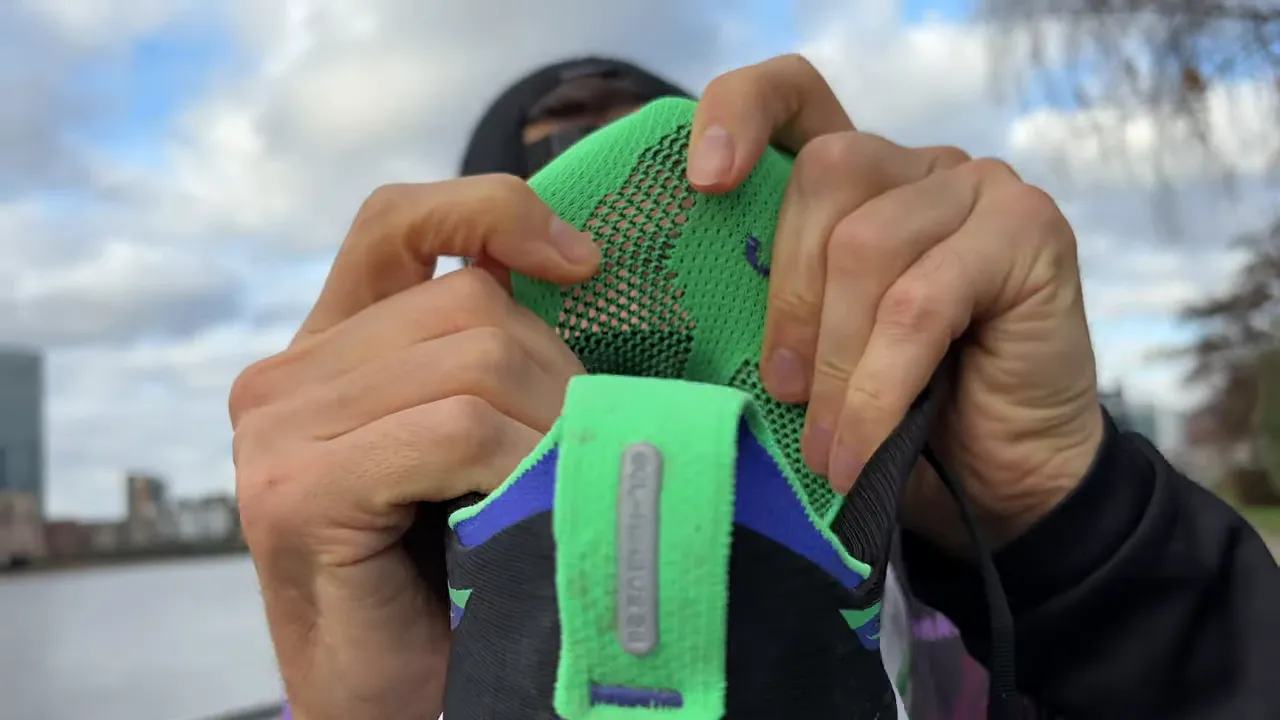 Close-up of an Asics Gel Nimbus 28 tongue being stretched to show the gusset and engineered knit upper.