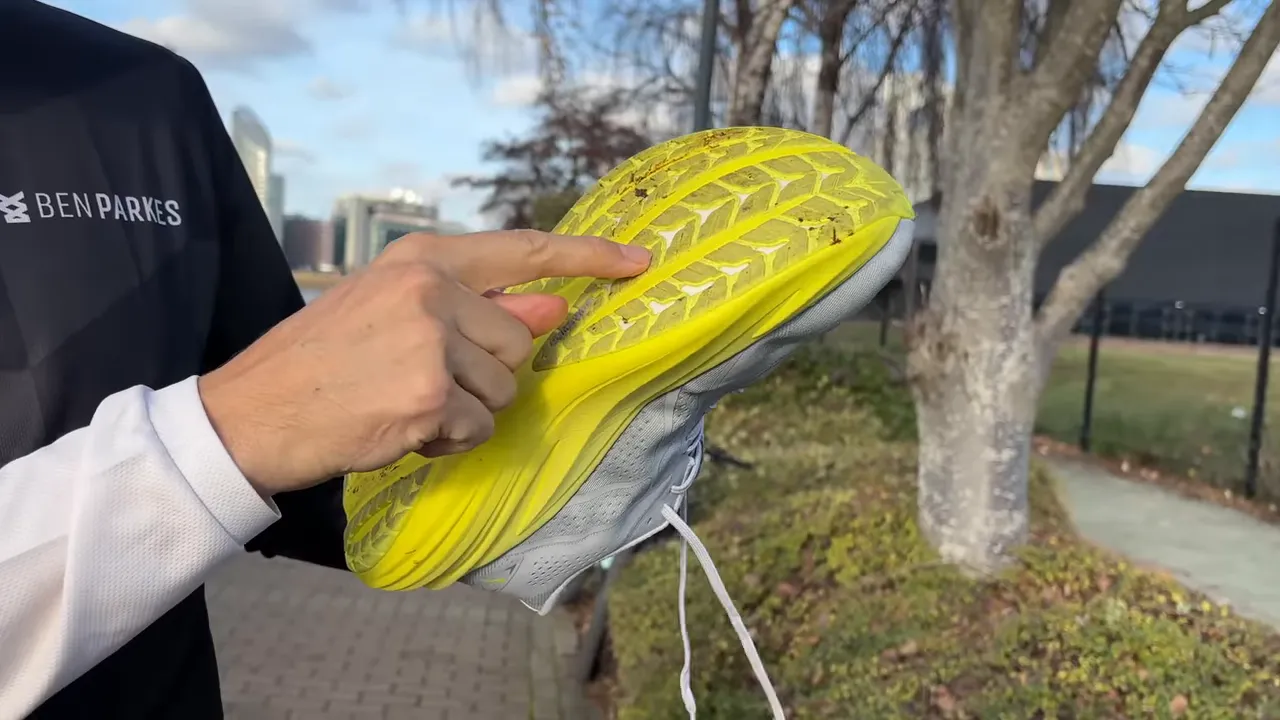 Reviewer pointing to the Puma MagMax 2 outsole showing rubber sections and sculpted yellow midsole