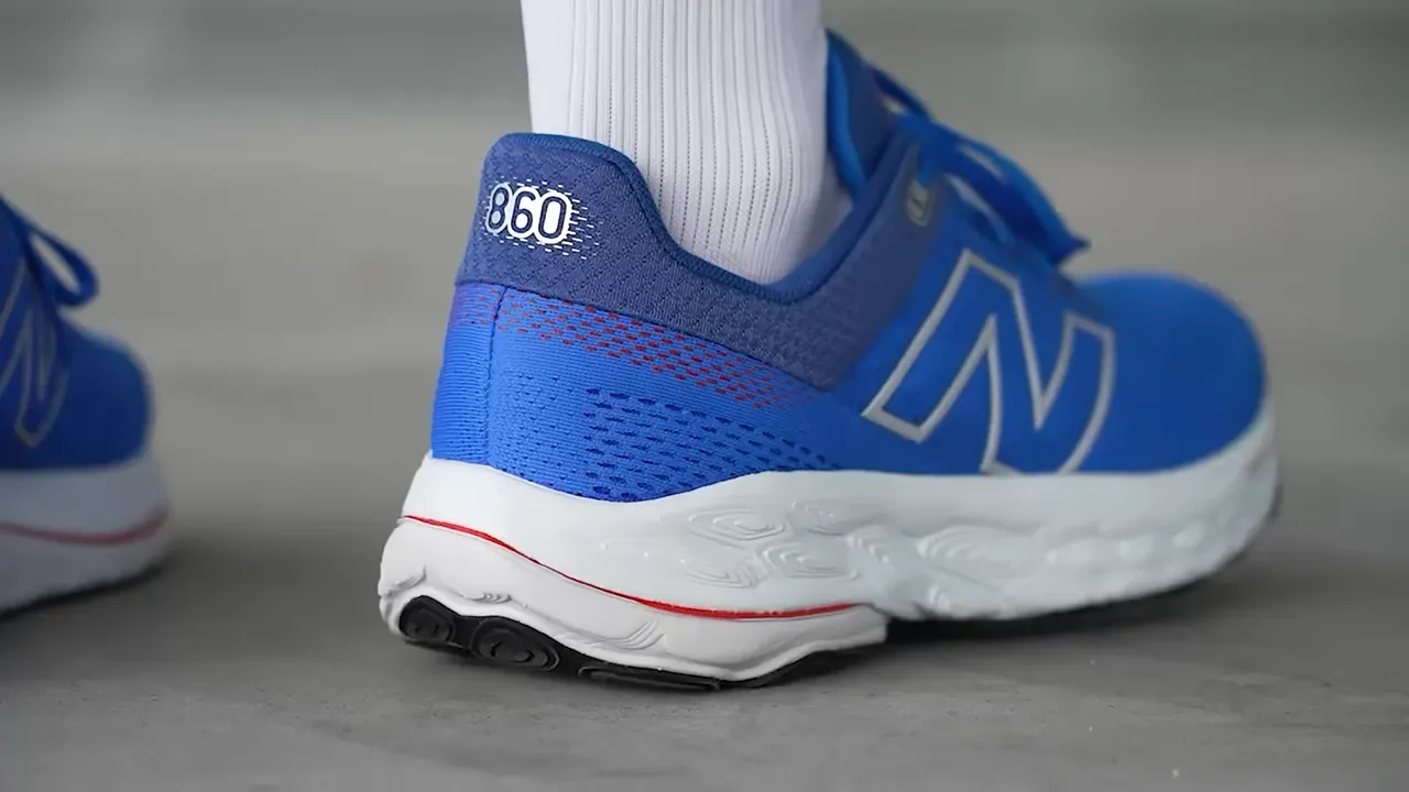 On-foot rear view of a blue New Balance 860 showing the heel collar and fit with sock
