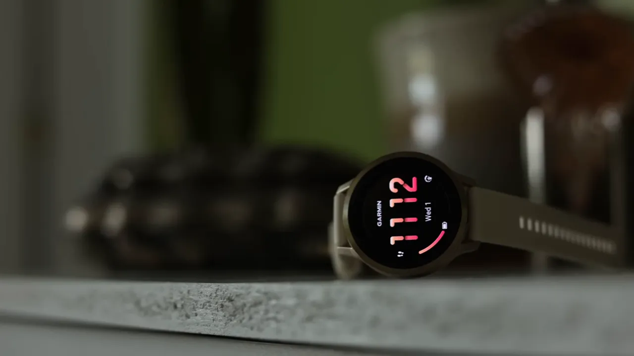 Garmin round smartwatch on a table showing the watch face and time with a shallow depth of field.