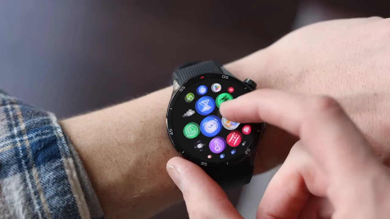 OnePlus Watch 3 on wrist with finger tapping the app grid, rotating crown visible