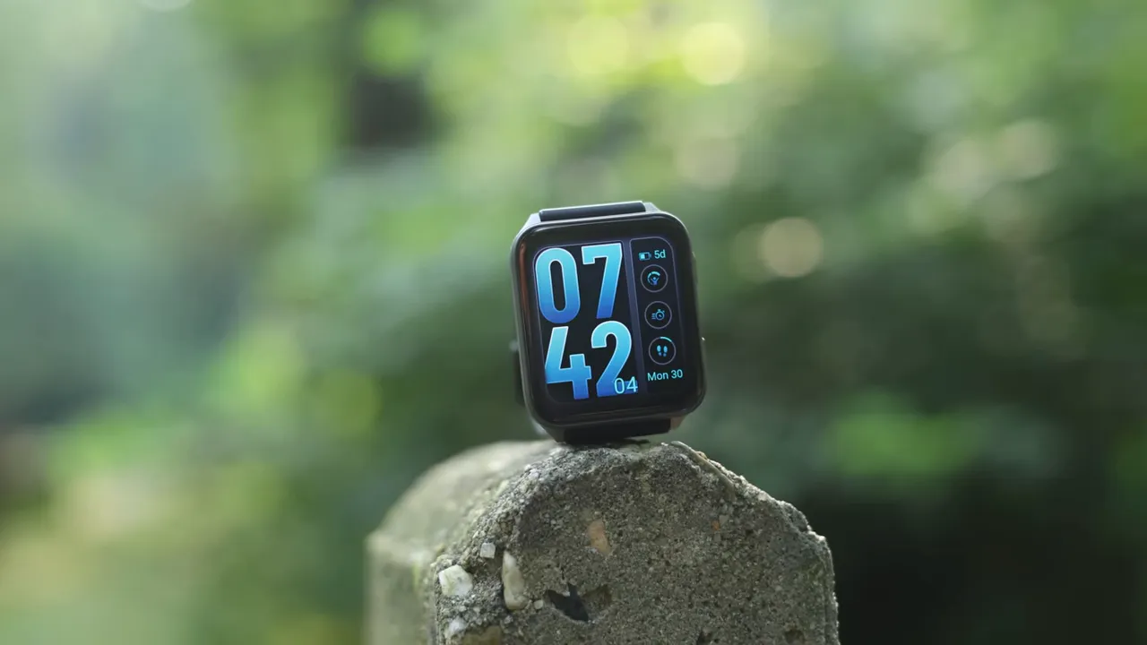Square smartwatch centered on a stone post showing a large blue digital watch face, clear and in-focus