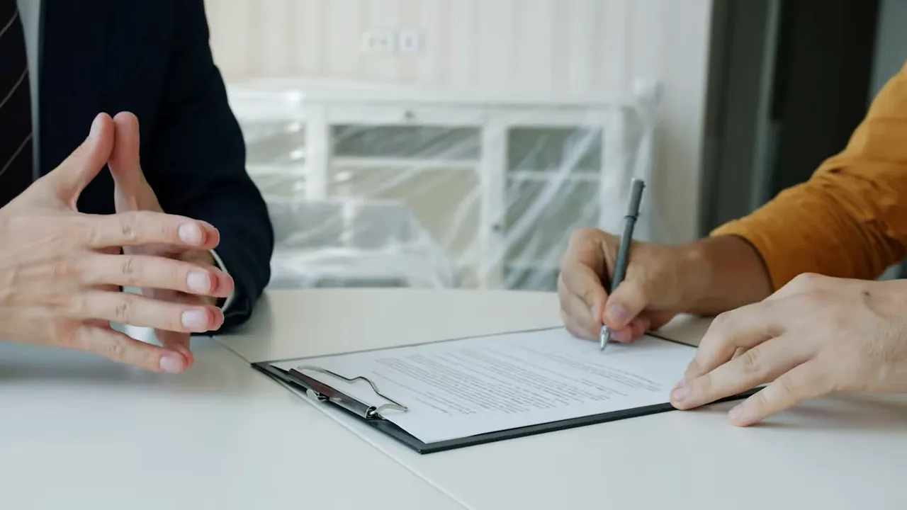 Hands signing real estate closing documents at a table