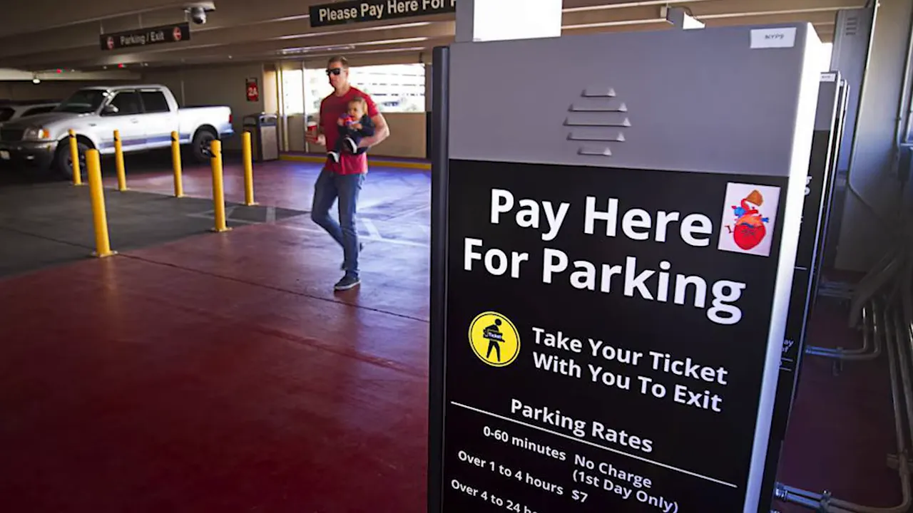 Parking garage pay station with sign reading 'Pay Here For Parking' and posted parking rates
