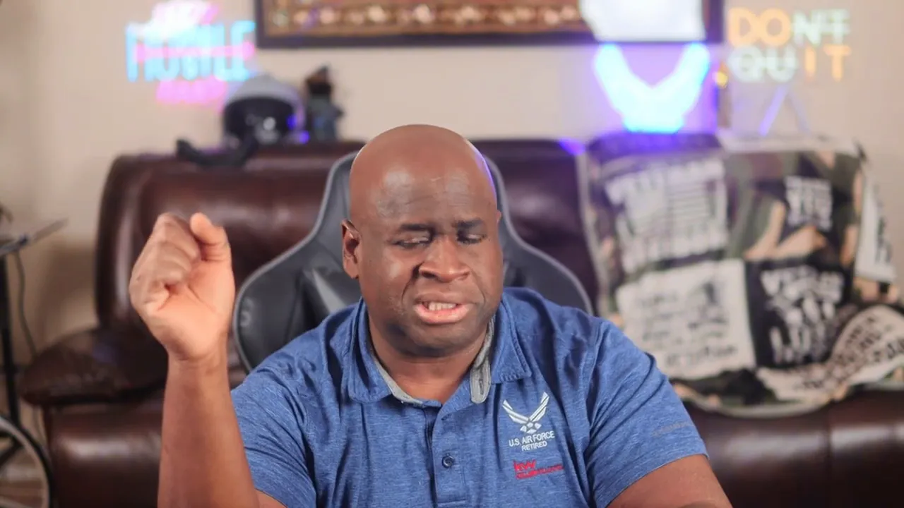 Presenter in a blue polo raising his hand while explaining budgeting tips in a home studio.