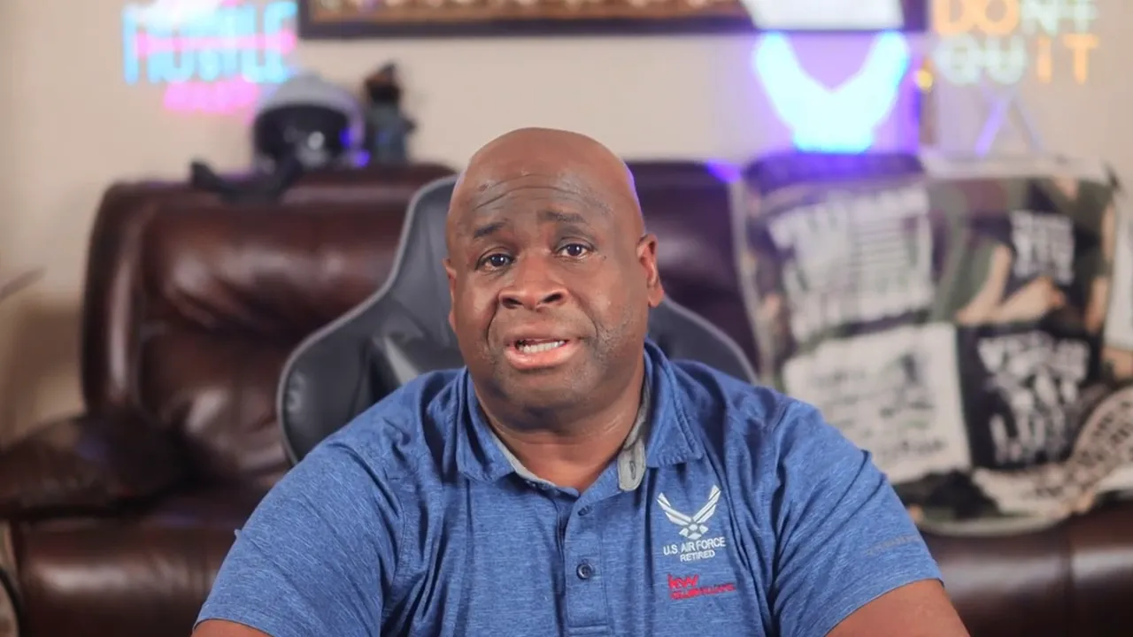Presenter in blue polo seated in a living-room setting, speaking about move-in costs