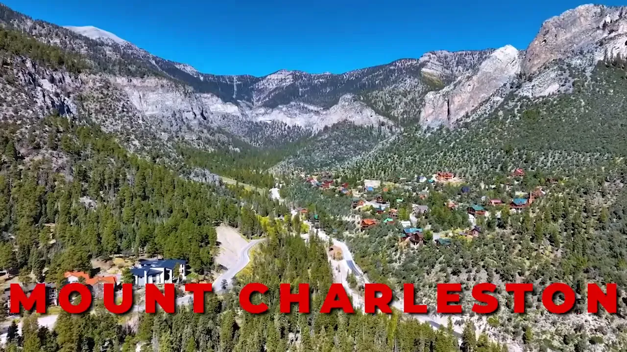 Aerial view of Mount Charleston valley with pine forests, cabins and rocky cliffs under a clear blue sky