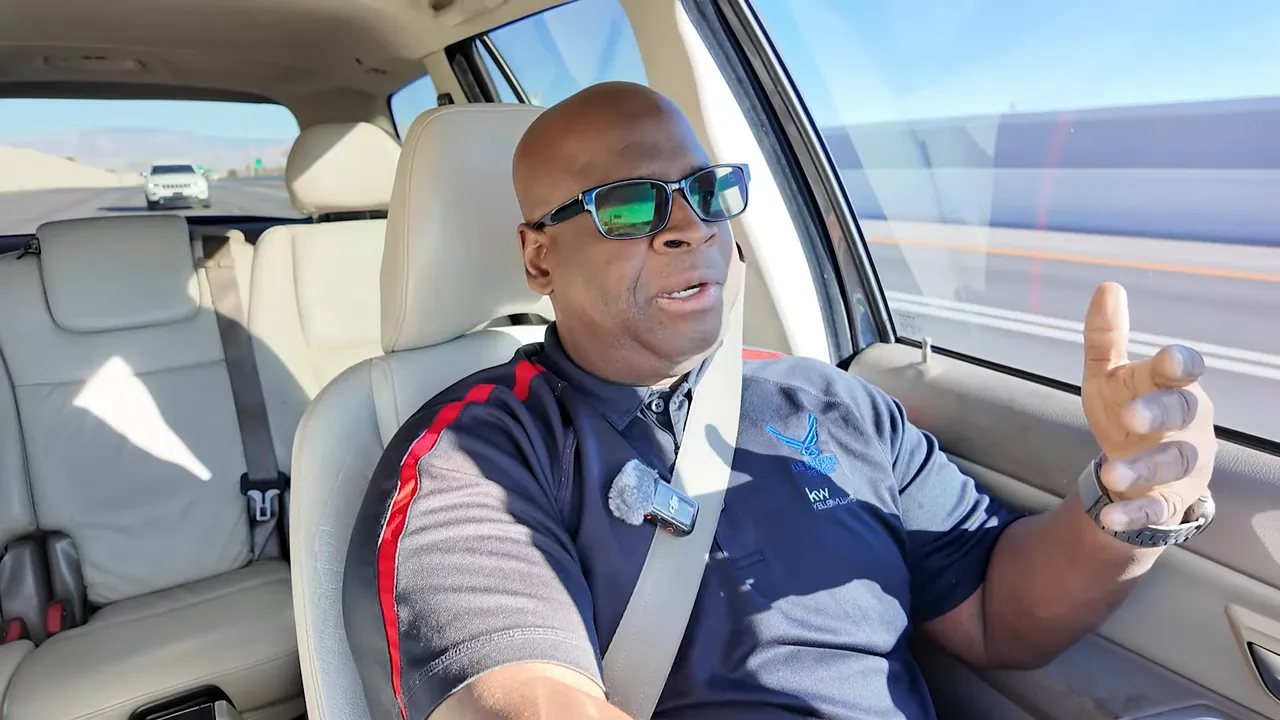 High-quality shot of a speaker in a car, clearly visible lapel mic and open hand gesture emphasizing preparedness.