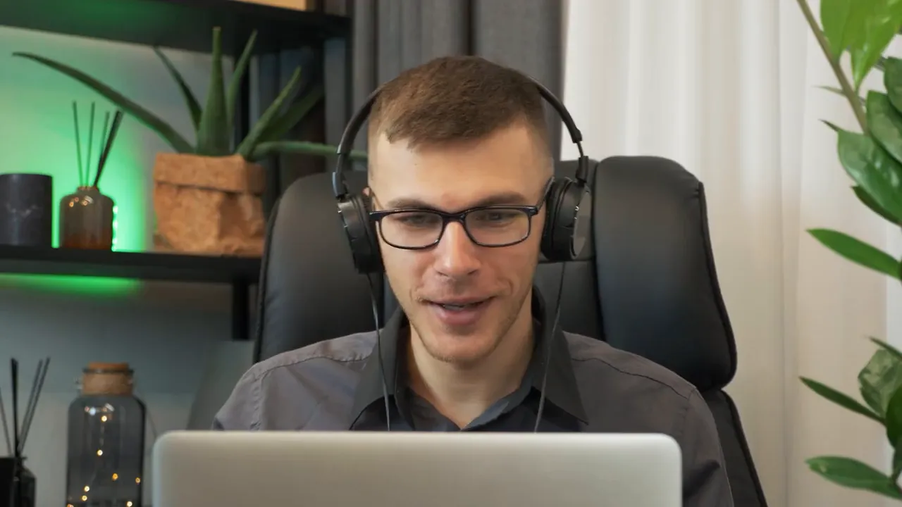 Agent on a video call with headphones on, looking at a laptop during a virtual home tour.