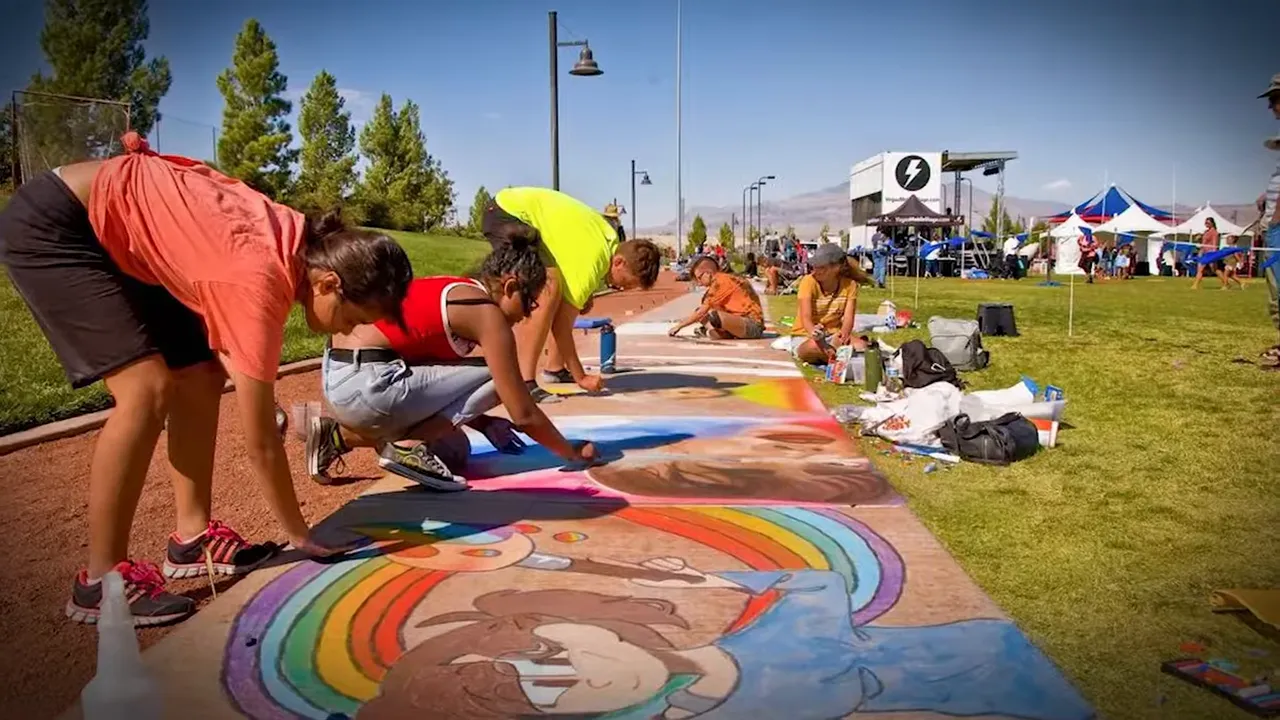 Families and children creating chalk art on a sidewalk at a sunny neighborhood park festival