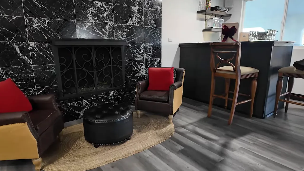Black marble fireplace with two accent chairs and a wet bar with stools
