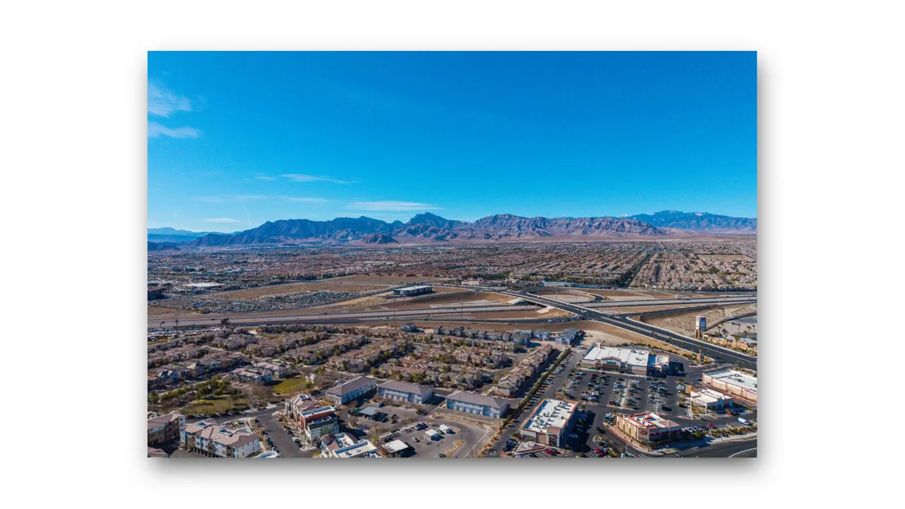 aerial view of suburban neighborhoods and a highway interchange with mountains in the distance, illustrating commute options