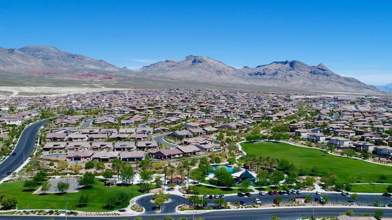 Aerial view of a Summerlin-style neighborhood with a large green park, residential streets, and mountains behind
