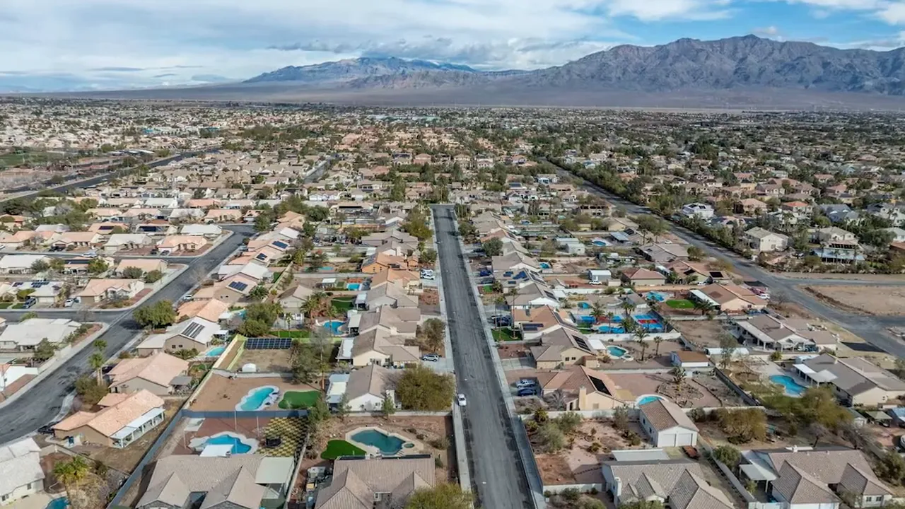 aerial view of suburban neighborhood with pools and mountains in the distance