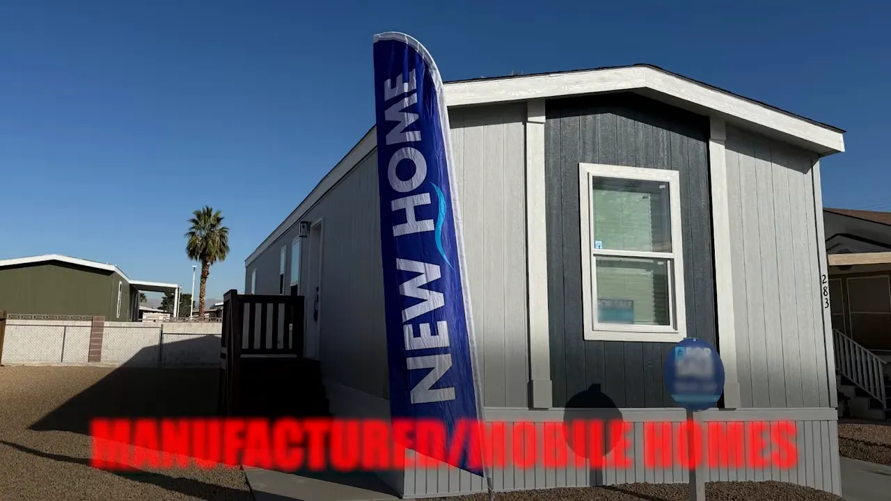 Manufactured home exterior with vertical banner reading manufactured/mobile homes under a clear sky