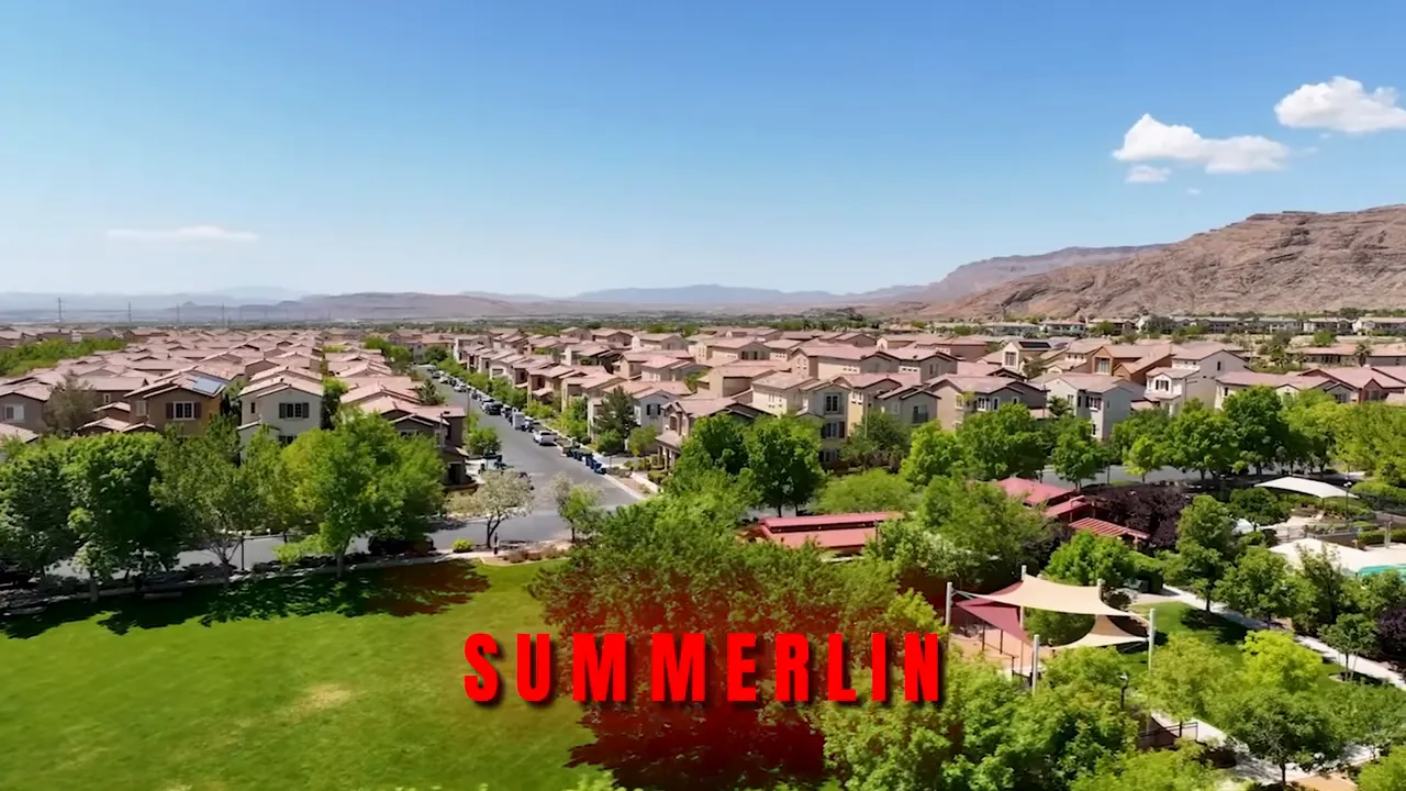 Aerial view of a Summerlin neighborhood showing rows of houses, green park space and surrounding desert hills under a clear blue sky.