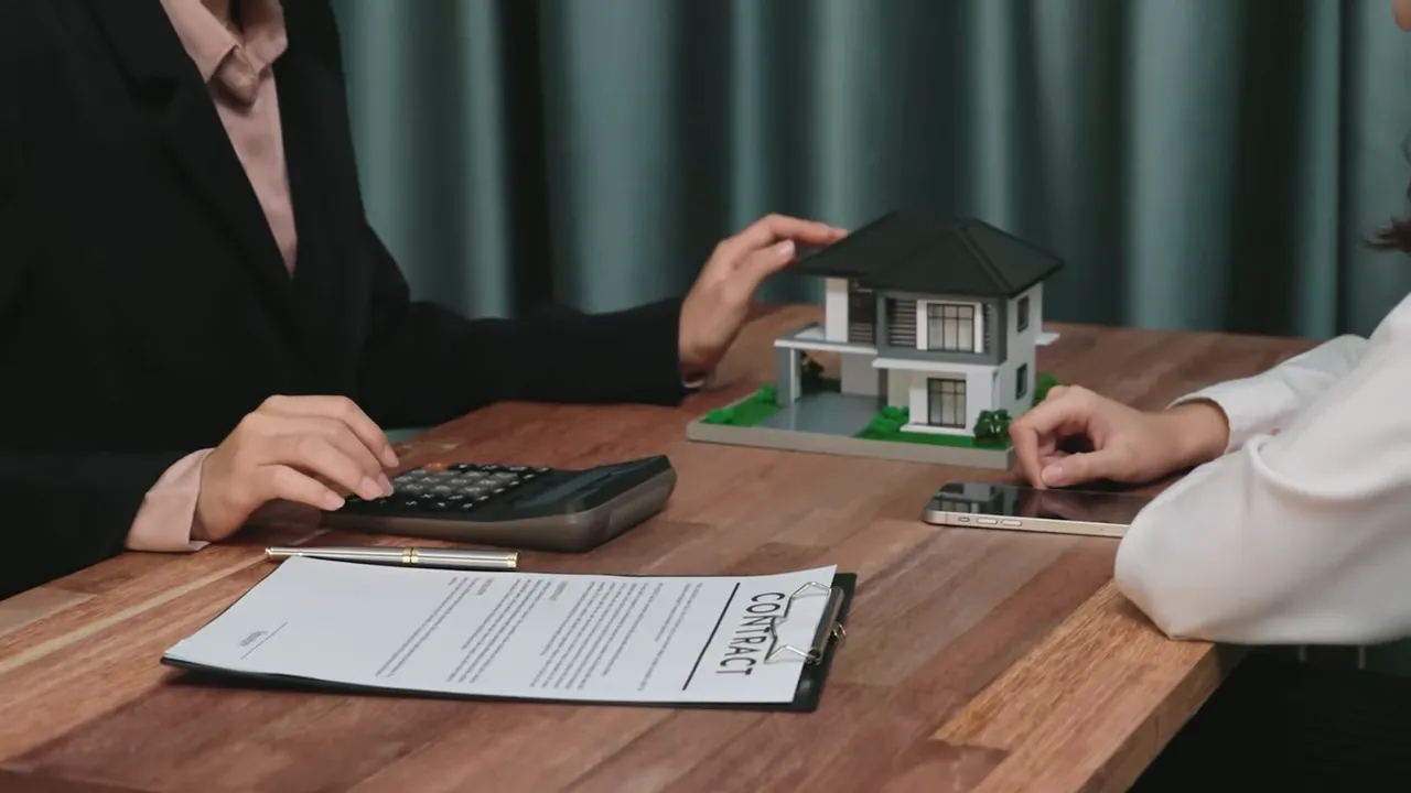 Close-up of a buyer contract on a clipboard with a small house model and a calculator, hands pointing at the model