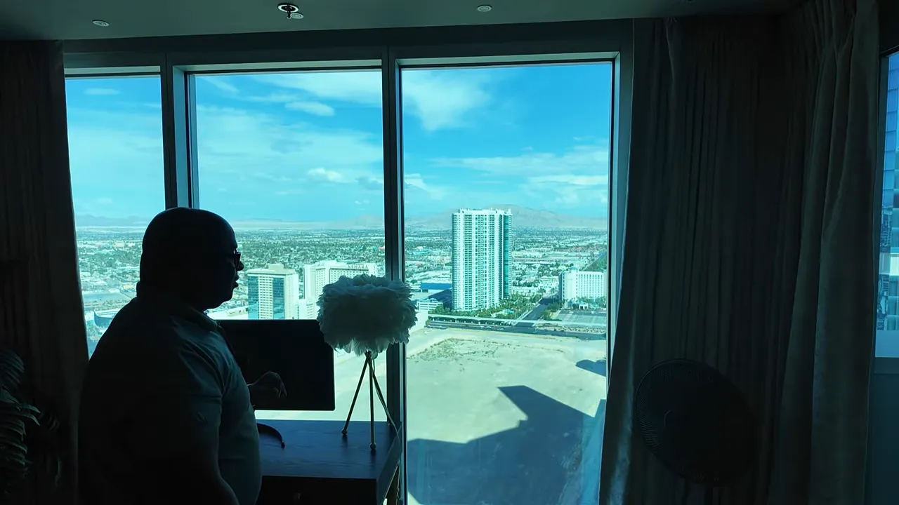 Silhouette of a presenter at a large living-room window with an unobstructed north-Strip view showing a nearby tower and distant mountains