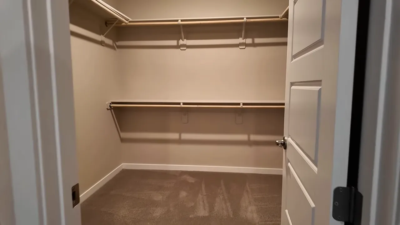 Spacious primary walk-in closet with tall interior door, shelving and hanging rods
