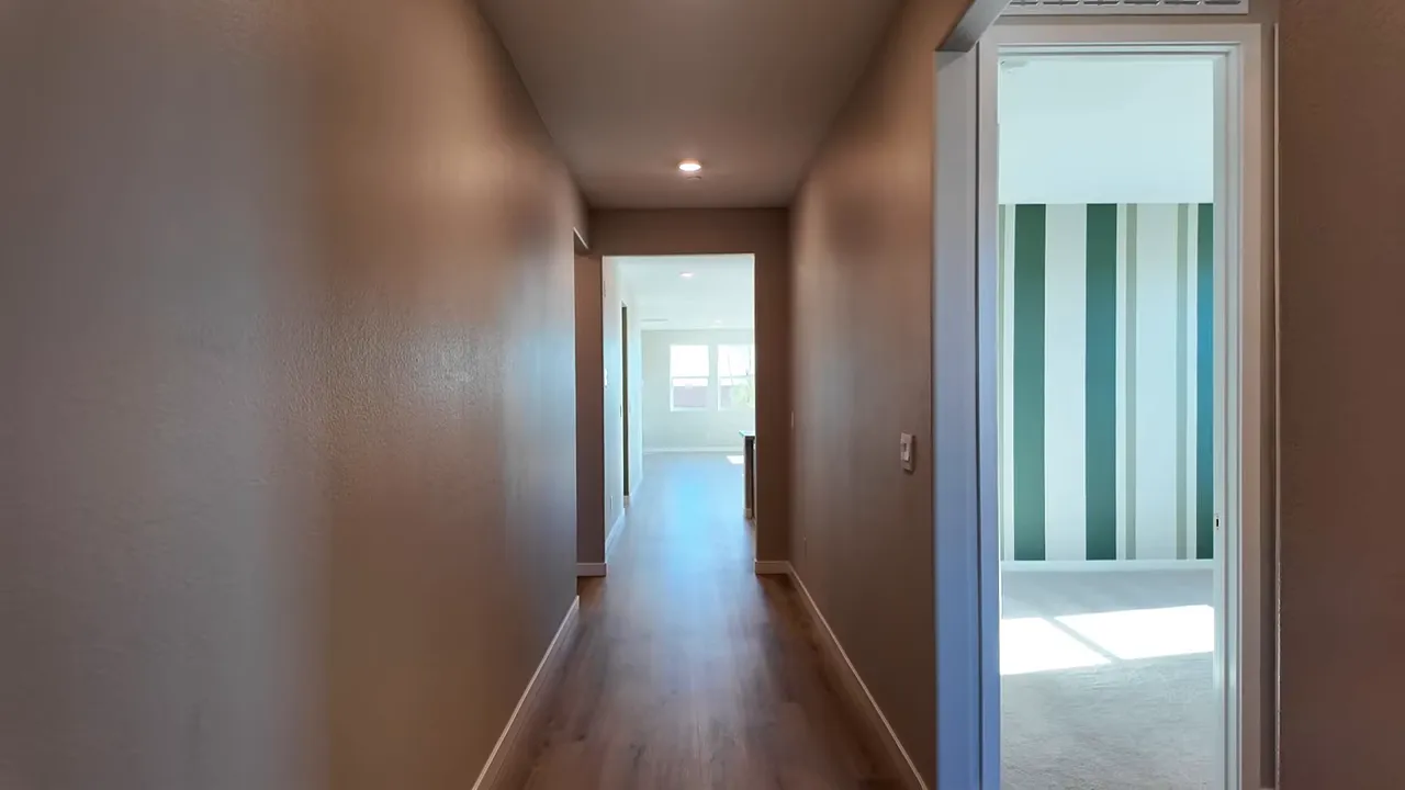 interior hallway showing ceiling height, wood flooring and open sightline to living areas at Heartland Grove